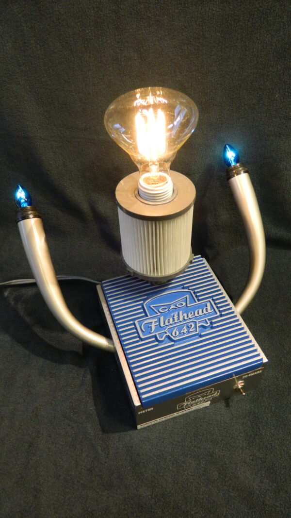 The Flathead 642 Lamp is a blue and silver Lamp built from a CAO Flathead box with automobile details such as pipes and a filter. - For the Car Enthusiast