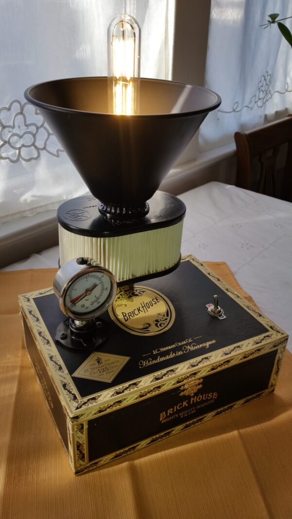 The Future is Now Lamp is Crafted from a Black & Gold Brick House Cigar Box, it shows it's steampunk tenancies with a gauge, an uplight shade and an Edison style bulb.