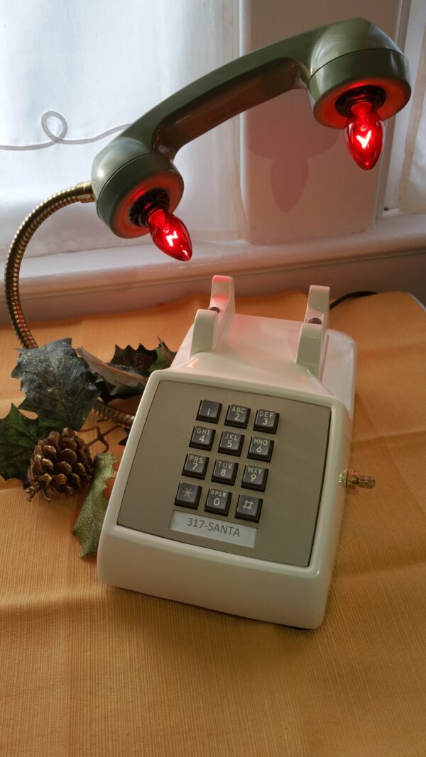 Santa's Hotline is a vintage cream touchstone phone with an avocado green handle. Red Lights glow from the receiver and Santa's Number on the phone. A red and white striped cord adds elegance.