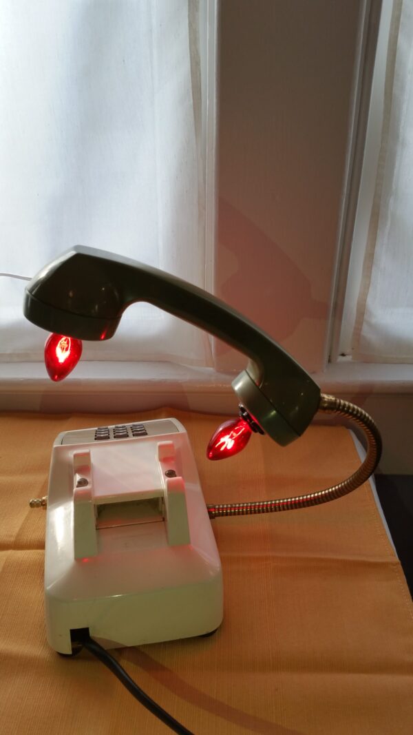 Santa's Hotline is a vintage cream touchstone phone with an avocado green handle. Red Lights glow from the receiver and Santa's Number on the phone. A red and white striped cord adds elegance.