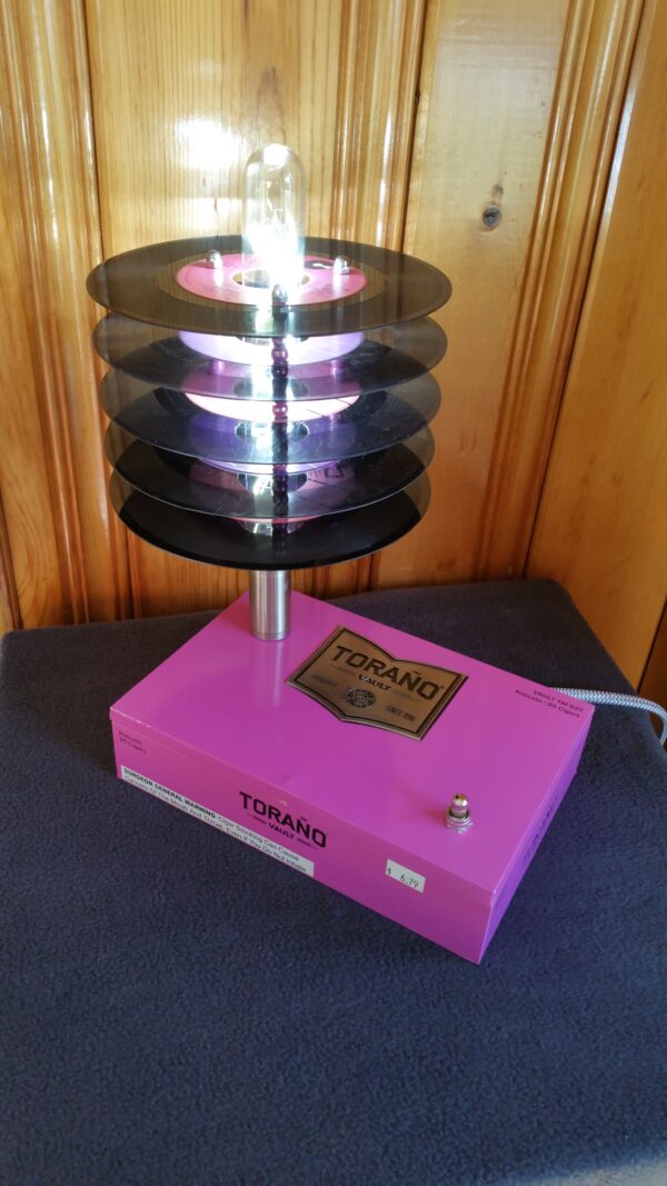 Front top view of Hot Pink Torano Cigar Box Lamp Topped with a stack of purple & pink labled 45 records which cause the lamp to have a subtle pink glow when lit.