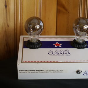 A dual bulb cigar box lamp that is predominately white in color with blue lettering and a red star. It reads, La Estrella Cubana